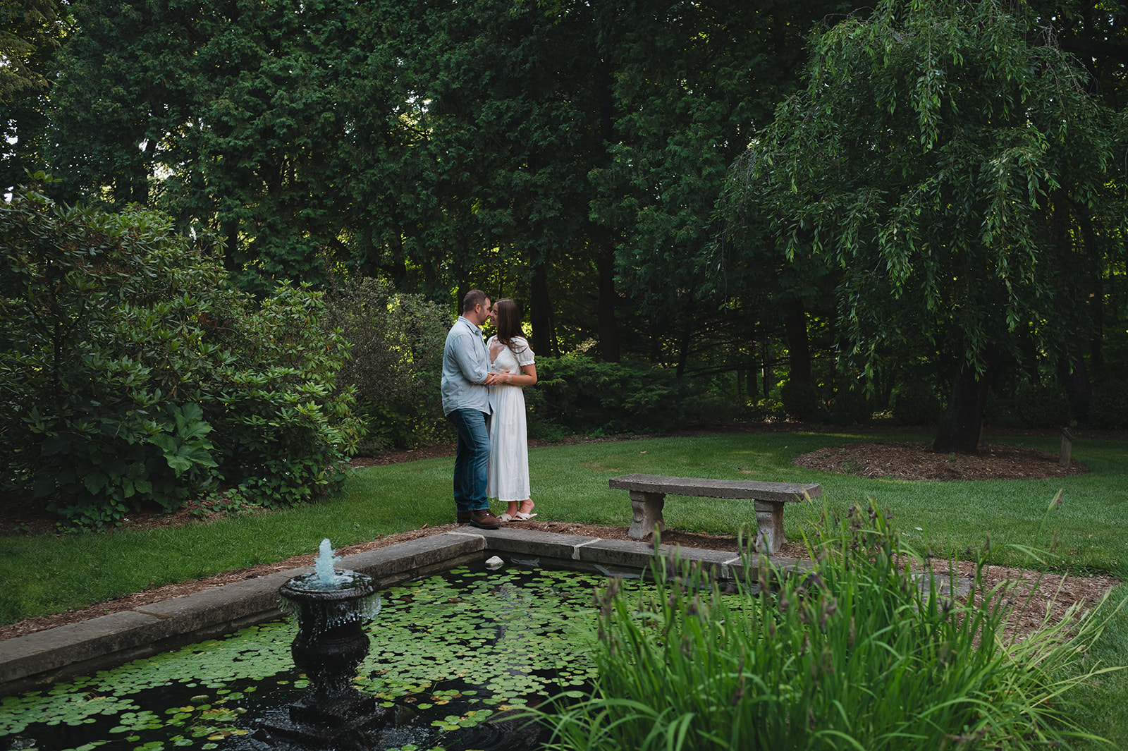 Couple kissing next to a lily pond at Aquinas College in Grand Rapids.
