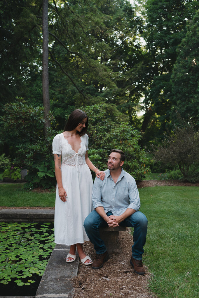 Couple standing next to a lily pond for their Grand Rapids engagement photos at Aquinas College.
