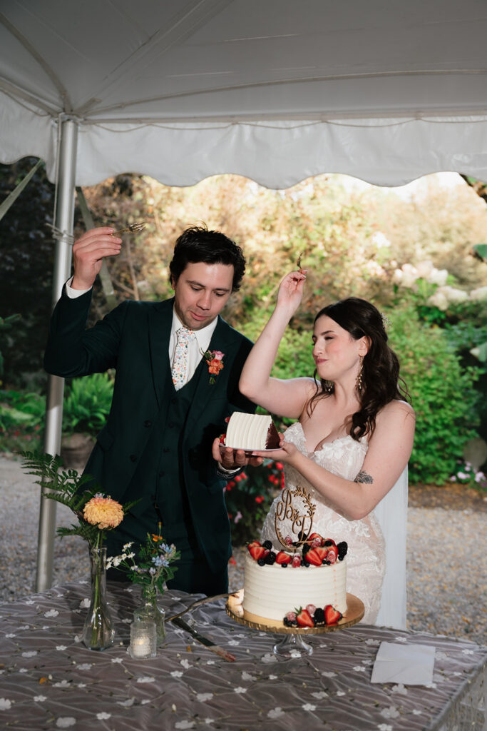 Bride and groom celebrating after cutting their wedding cake beneath the reception tent.