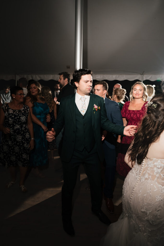 Groom dancing with guests beneath the market lights at the wedding reception.