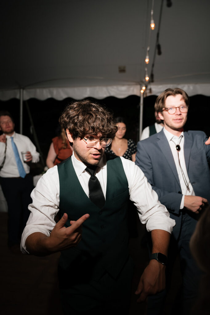 Wedding guest wearing a dark green vest dancing during the reception.