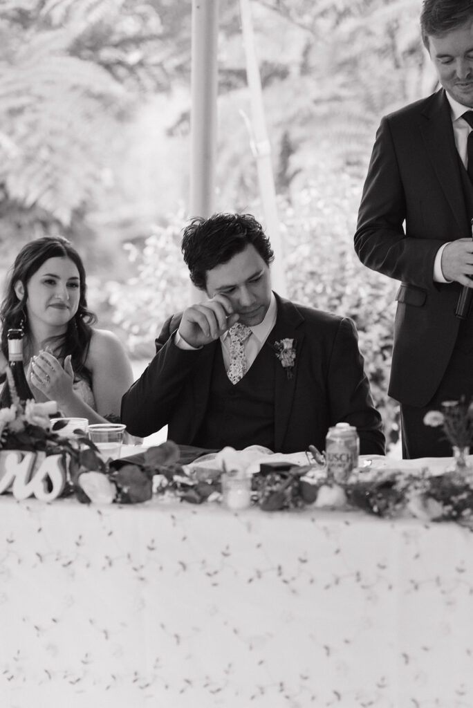 Black and white photo of the groom getting emotional during speeches.