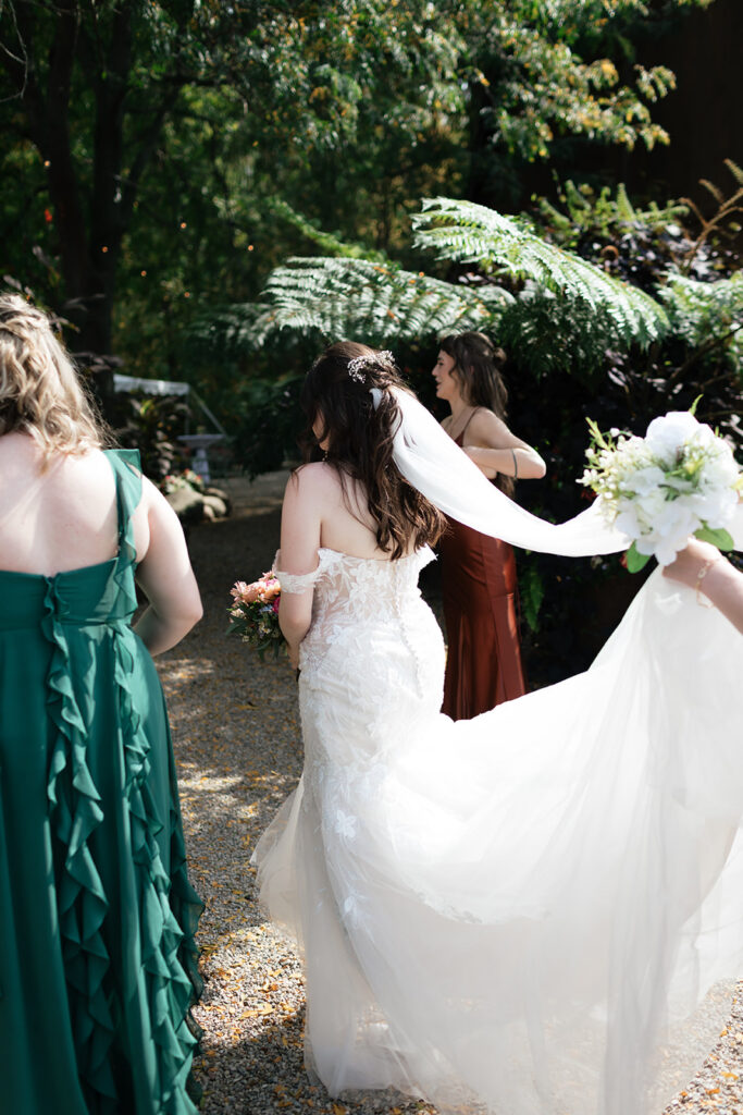 Candid photo of a bride walking with her bridesmaids in the gardens for portraits. 