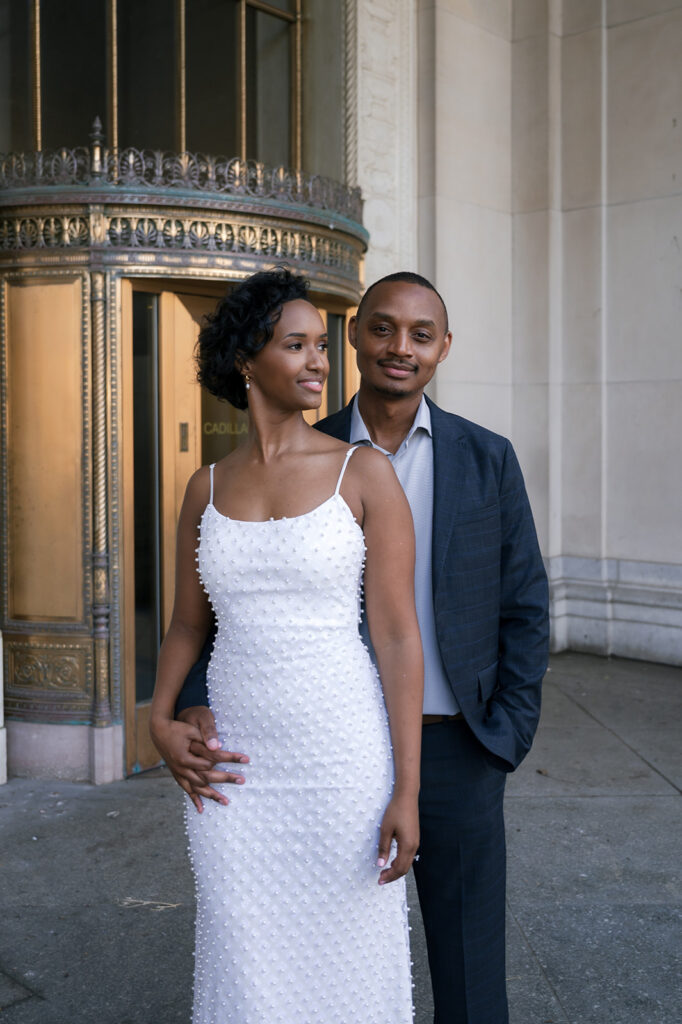 Couple posing outside of Cadillac Place for their Detroit engagement photos.