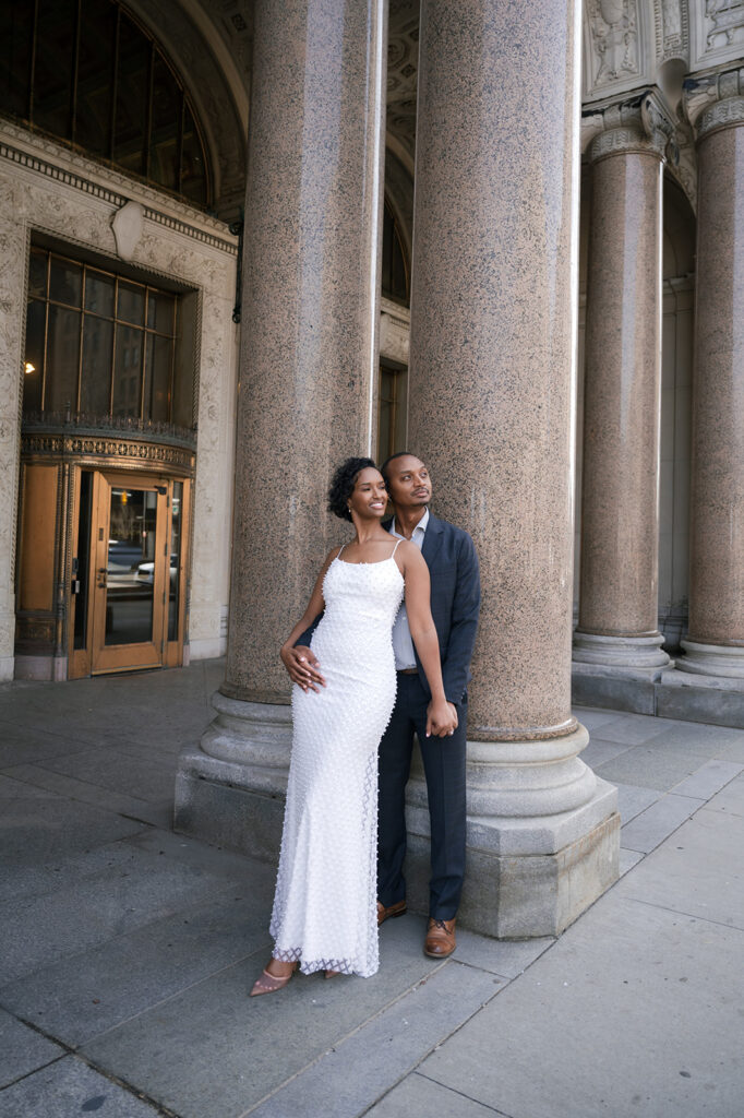 Couple posing outside of Cadillac Place for their Detroit engagement photos.