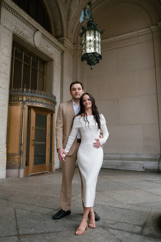 Couple posing outside of Cadillac Place for their Detroit engagement photos.