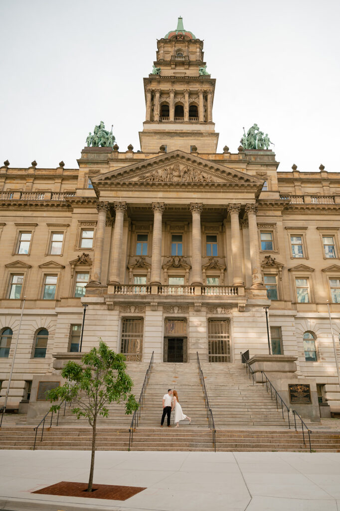Couple posing on the stairs of Detroit Courthouse for their engagement photos.