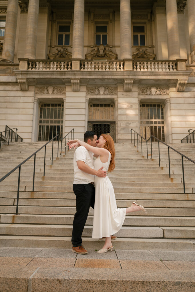 Couple kissing on the stairs of Detroit Courthouse for their engagement photos.