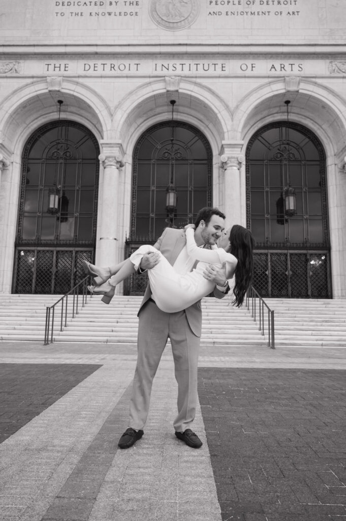 Black and white engagement photo of a couple outside of The Detroit Institute of Arts. 