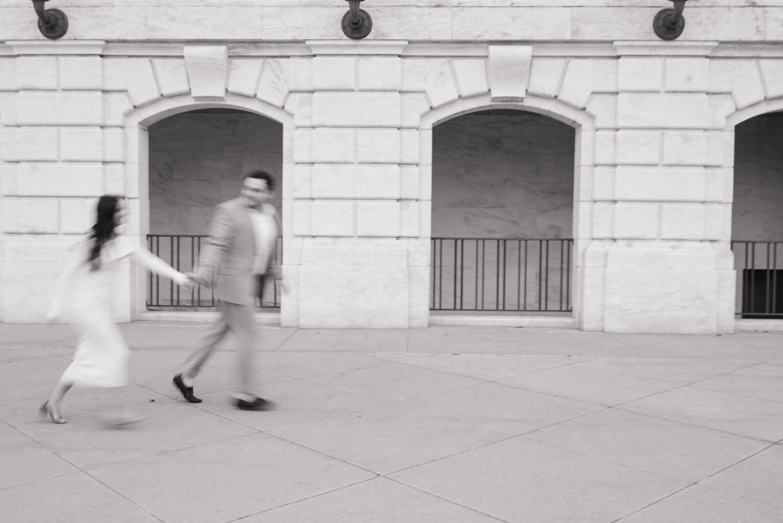 Black and white motion blur photo of a couple running outside of The Detroit Institute of Arts. 