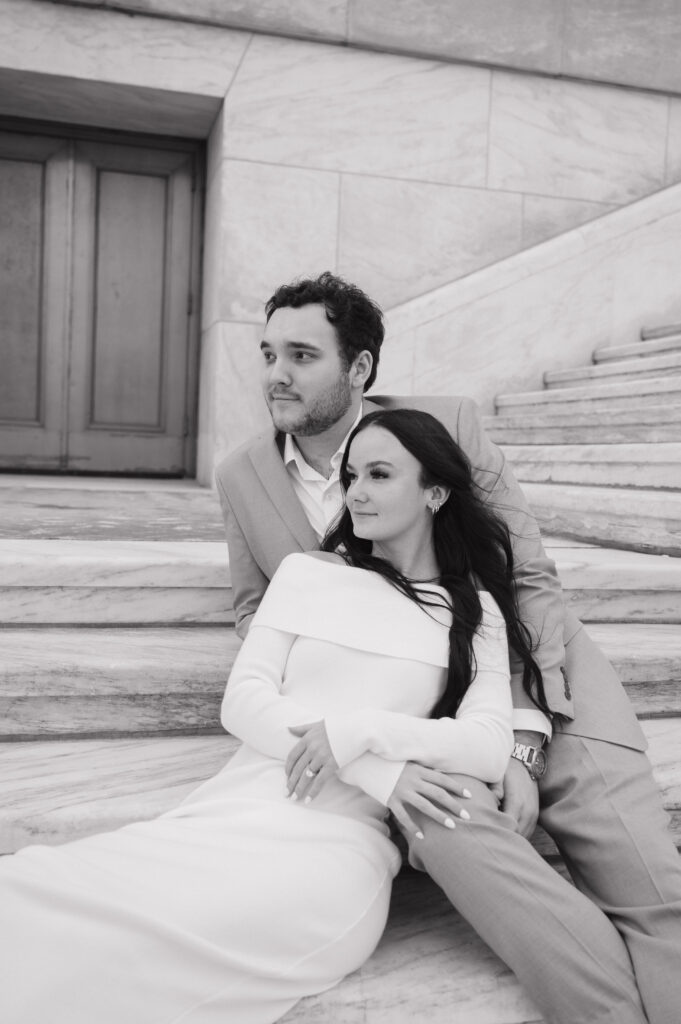 Black and white photo of a couple sitting on the stairs outside of The Detroit Institute of Arts. 