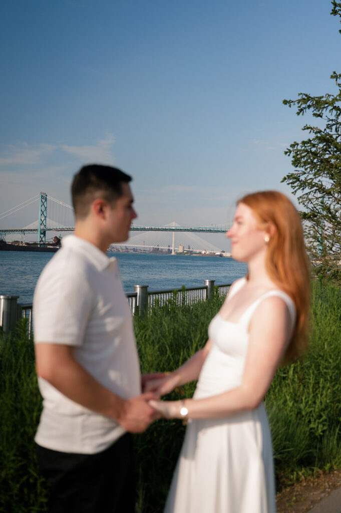 Couple holding hands during their Detroit engagement photos on The Riverwalk. 