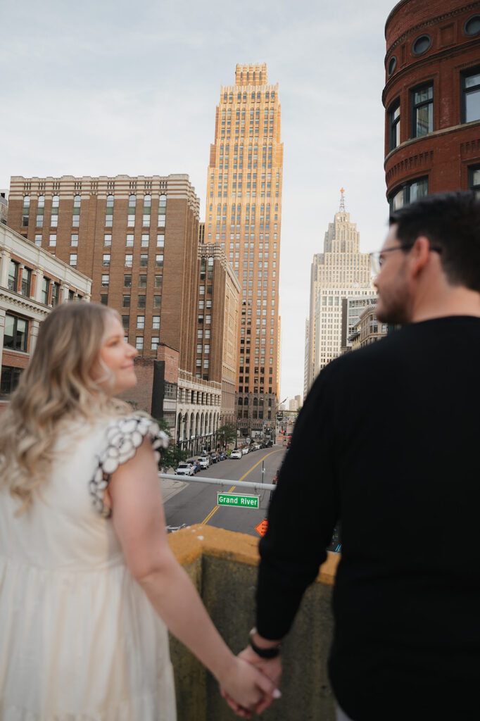 Couple holding hands on a rooftop for their Detroit engagement photos.