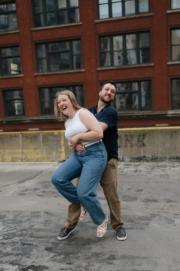 Couple being playful during their Detroit engagement photos on a rooftop.