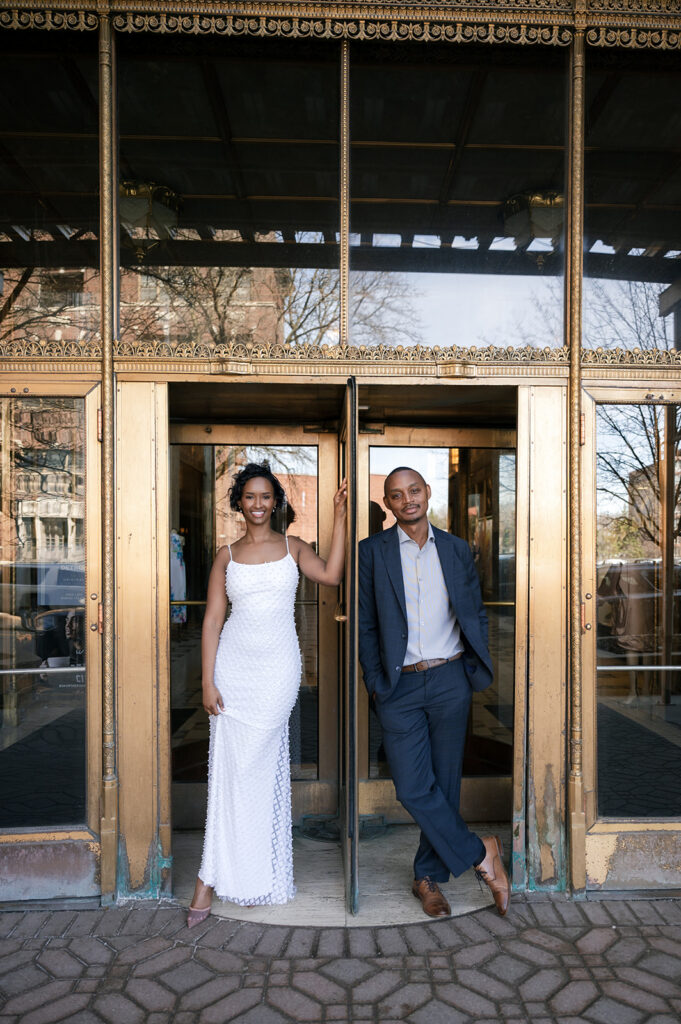 Couple posing outside at the doorway of Fisher Building for their Detroit engagement photos.