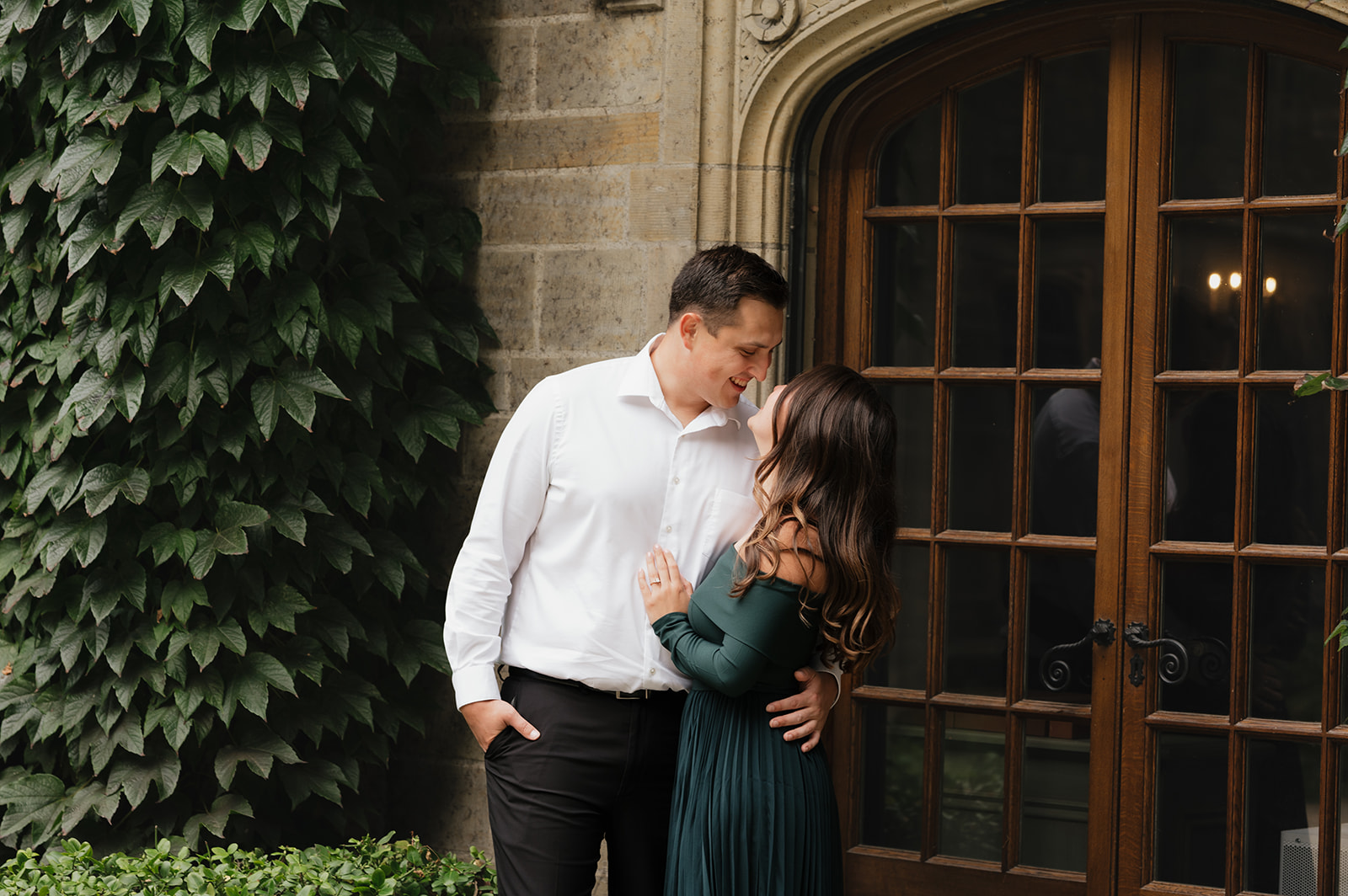 Couple smiling at each other near big glass doors. 