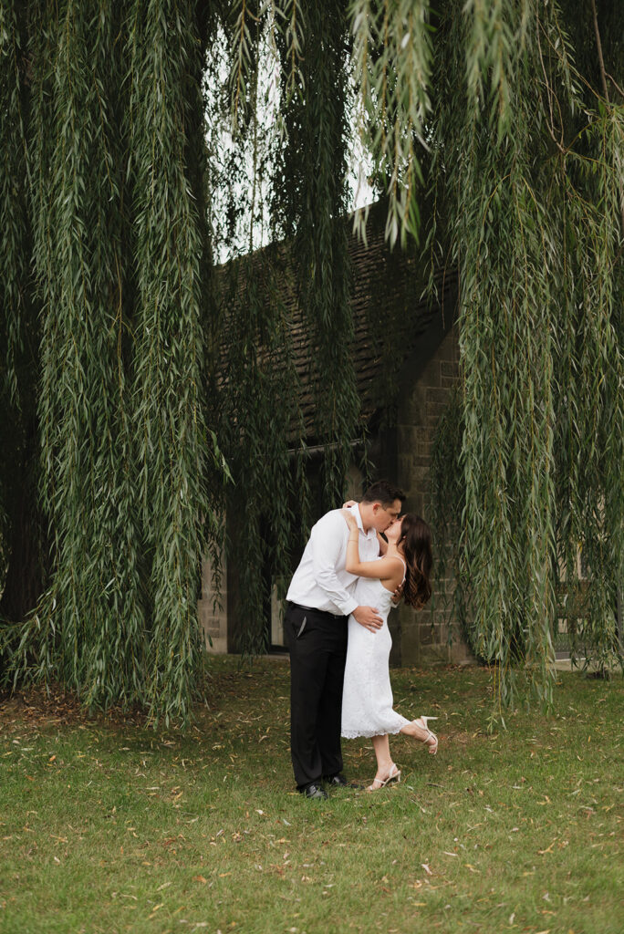 Couple kissing beneath a willow tree. 