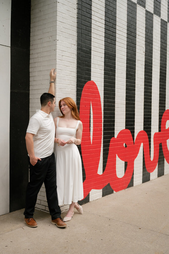 Couple posing by the Love Graffiti wall for their Detroit engagement photos.