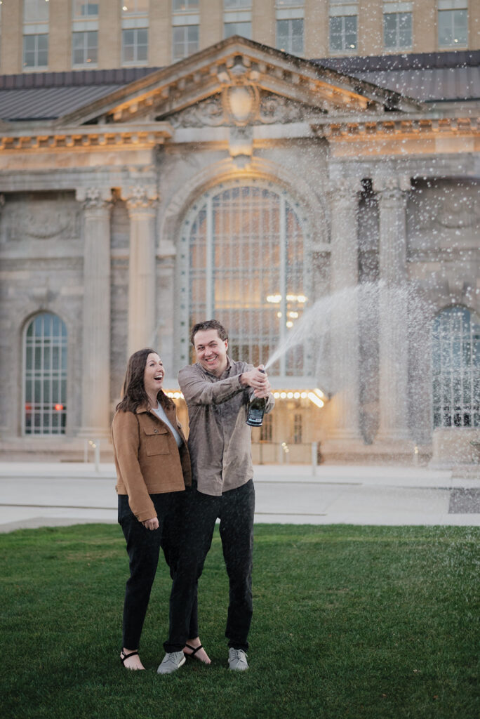 Couple popping champagne during their engagement session.