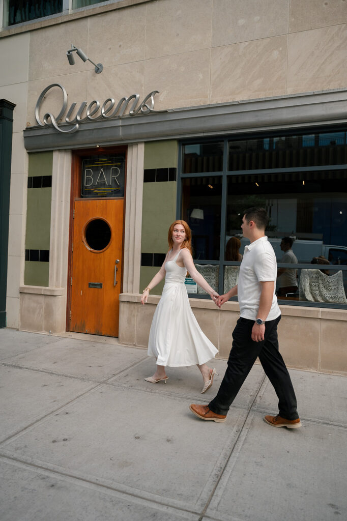 Couple walking outside of Queens Bar for their Detroit engagement photos.