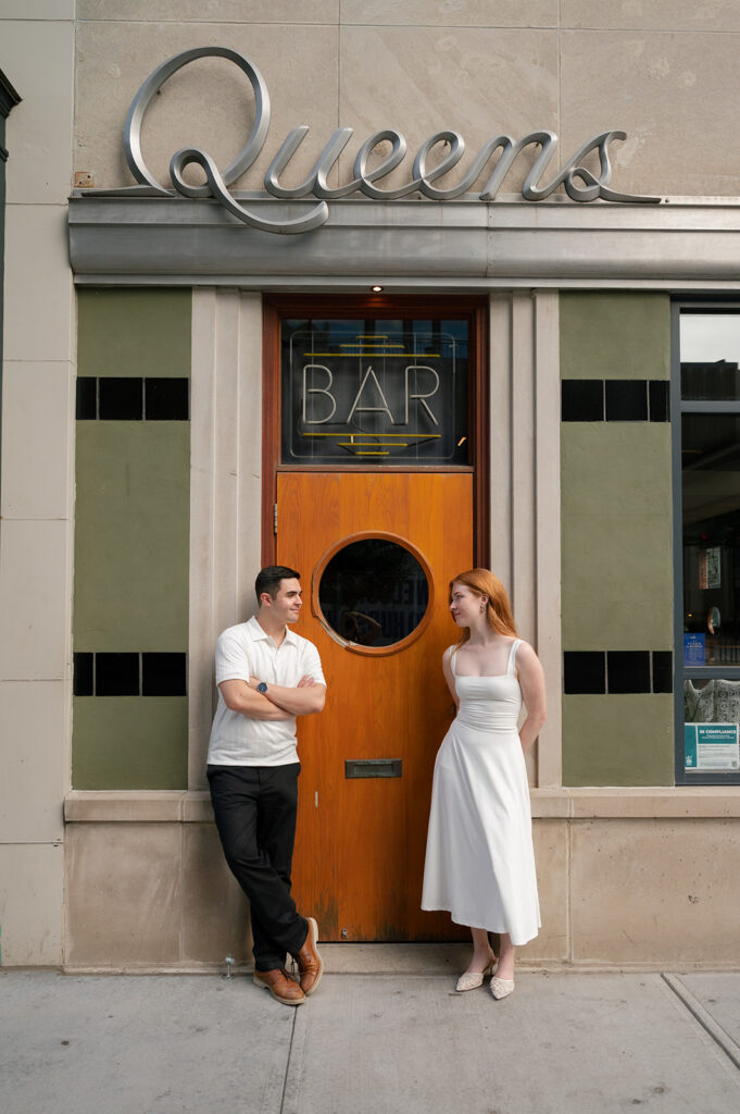 Couple posing outside of Queens Bar for their Detroit engagement photos.