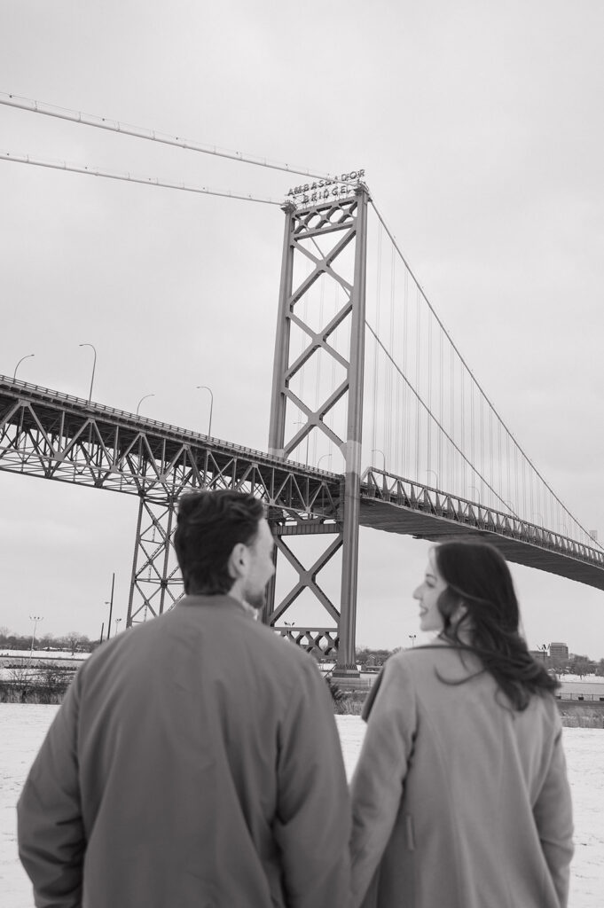 Black and white winter engagement photos in Detroit with Ambassador Bridge in the background. 