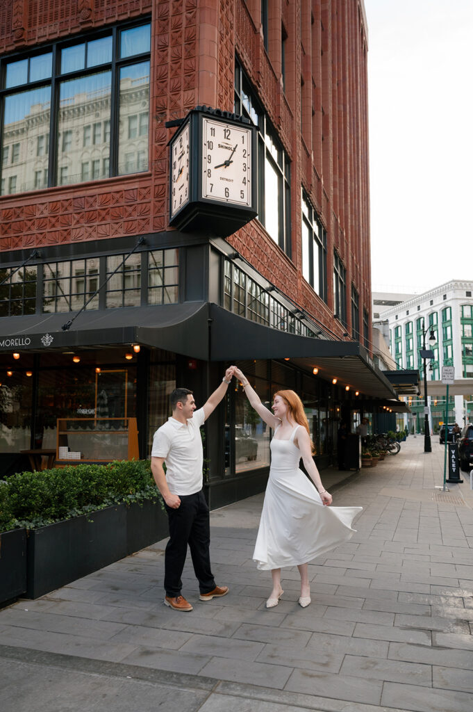 Couple dancing under the Shinola Hotel clock for their Detroit engagement photos.